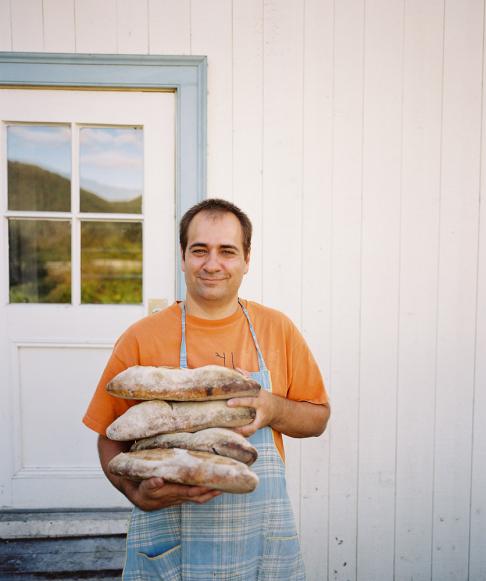 The baker with fresh loaves of bread outside 'Boulangerie La Remy' in Baie Saint-Paul, Charlevoix, Quebec.