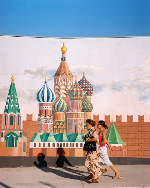 Two women walk by a wall depicting the Kremlin in front of Ashgabat's (Turkmenistan) amusement park, locally known as 'Disneyland'.