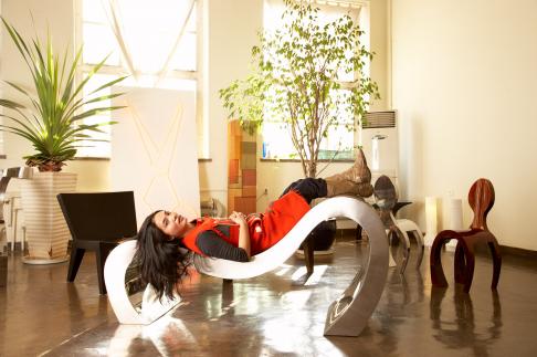 Lin Jing at her studio in the 798 Art complex in Beijing, also known as Dashanzi. Lin Jing is reclining on a piece called 'Long Island' made of aluminum.